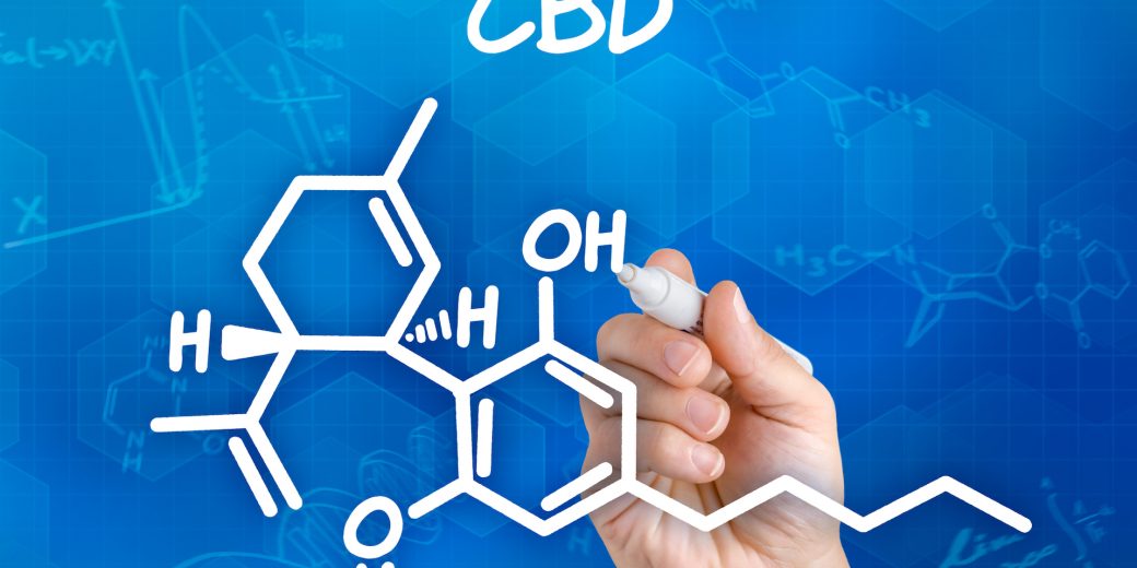 Hand with pen drawing the chemical formula of CBD