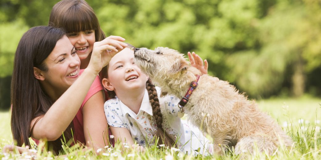Mother and daughters in park with dog smiling